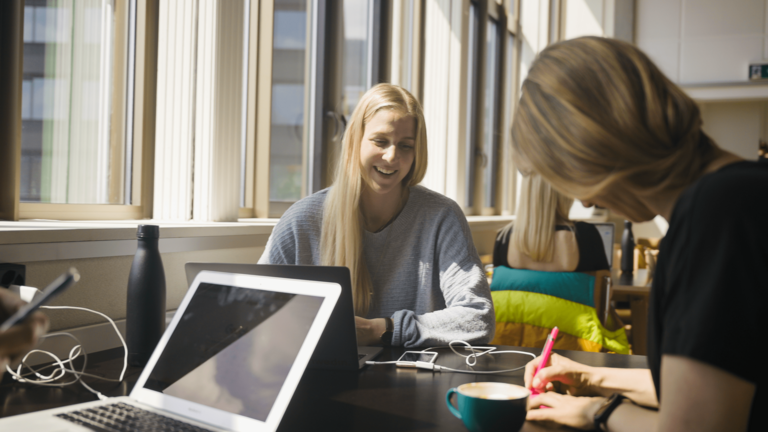 Zwei Mitarbeiterinnen sitzen am Tisch und erarbeiten eine Social-Media-Strategie